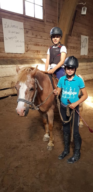 Enfants avec un cheval dans le manège de Château-d'Oex pendant un camp d'équitation à l'école d'équitation de Jean Blatti